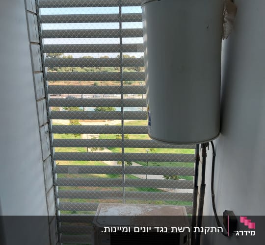 דוד שמש ומזגן ליד רשת הגנה על חלון